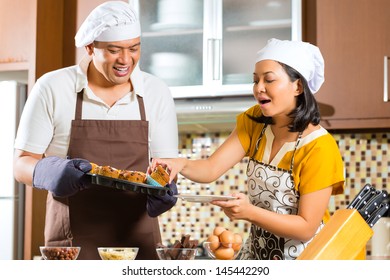 Asian couple, man and women, baking homemade cake in his kitchen for dessert - Powered by Shutterstock