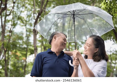 Asian couple of middle-aged man and woman holding umbrella together after the light rain, concept for couple family care and togetherness, health care, couple family wellness - Powered by Shutterstock