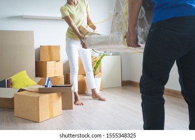 Asian Couple Moving Heavy Furniture To New Home.