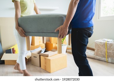 Asian Couple Moving Heavy Furniture To New Home.