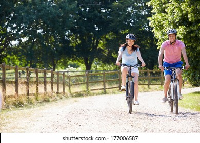 Asian Couple On Cycle Ride In Countryside