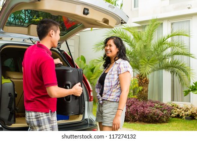 Asian Couple Packing Car With Suitcases For Holiday And Smiling