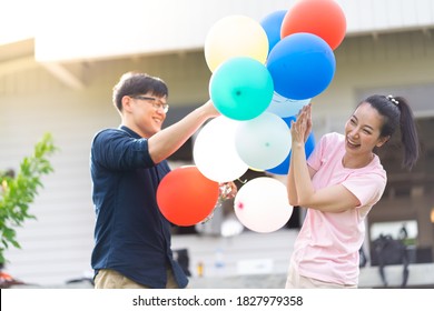 Asian Couple Playing And Tease Each Other With Balloon In The Garden 