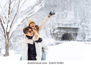 Asian couple playing together during travel forest mountain ski resort covered in snow on winter holiday vacation. Man and woman enjoy and fun outdoor lifestyle travel local town in Japan in snowy day - Powered by Shutterstock