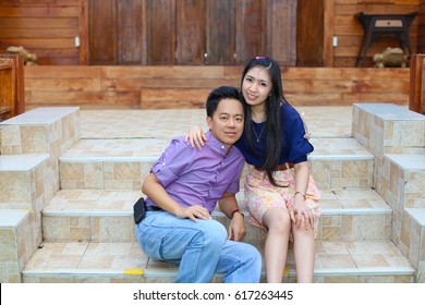 Asian Couple In Purple Dressing Sitting On A Step In Front Of A Wooden House