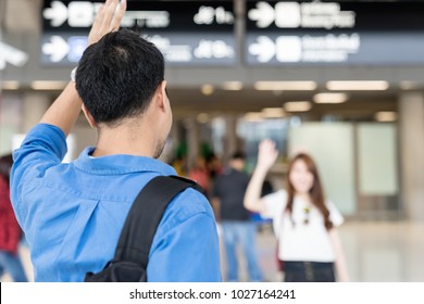 Asian Couple Say Hi Or Goodbye For Abroad At Airport. Back Asian Man Waving Hand Goodbye Girlfriend. Travel ,airport Terminal Concept.