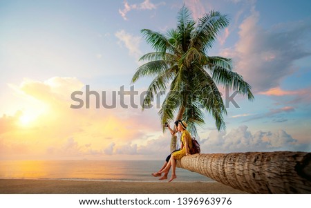 Asian couple selfie by camera on coconut palm tree in Kho Mak island, Kood, Trat, Thailand, this image can use for summer, beach, travel and valentine concept