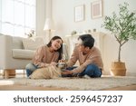 Asian couple shares a joyful moment while playing with their pet dog in a living room. relaxation and bonding.