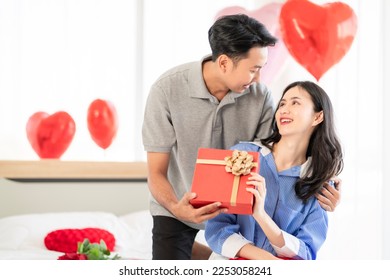 Asian couple Showing love surprise giving flowers or gifts to each other on important occasions such Valentine's Day birthdays or wedding anniversaries with love and warmth in bedroom of their home - Powered by Shutterstock