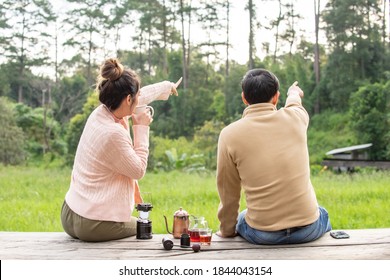 Asian Couple Sitting On Balcony At Resort And Drinking Hand Drip Coffee With Looking At Beautiful Nature In The Morning. Man And Woman Tourist Relax And Enjoy Outdoor Lifestyle And Holiday Vacation.