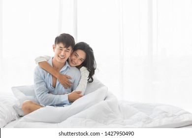 Asian Couple Sitting On Bed Together, They Hug Each Other With Love, Concept For Spending Time With Lover.