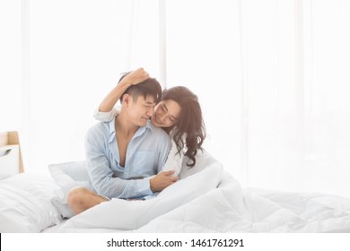 Asian Couple Sitting On Bed Together, They Hug Each Other With Love, Concept For Spending Time With Lover.