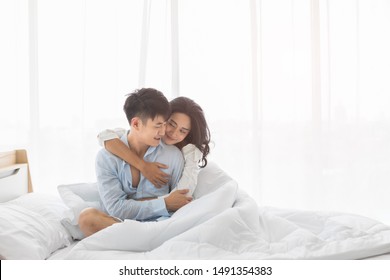 Asian Couple Sitting On Bed Together, They Hug Each Other With Love, Concept For Spending Time With Lover.