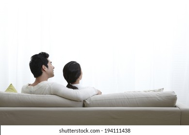 Asian Couple Sitting On Couch