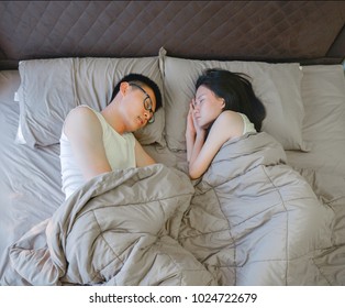 Asian Couple Sleeping On Brown Bed In Bedroom