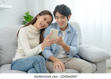 Asian couple smiling and happily use smartphone to online shopping. Husband ready to pay birthday present for beautiful wife. Find accommodation online for honeymoon, App online, book flight tickets. - Powered by Shutterstock