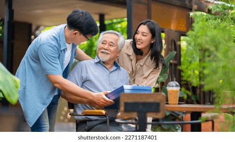 Asian couple surprised elderly father with Birthday gift at outdoor cafe restaurant on summer holiday vacation. Family relationship, celebrating father's day and older people health care concept. - Shutterstock ID 2271187401