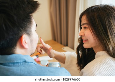 Asian Couple Traveler Having Romantic Moment In Bedroom. Woman Applying Vaseline On Her Boyfriend Lips.