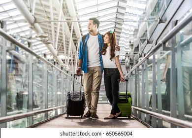 Asian Couple Traveler With Suitcases At The Airport. Lover Travel And Transportation With Technology Concept