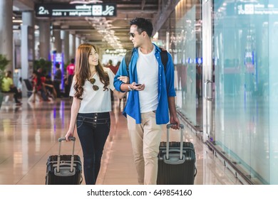 Asian Couple Traveler Walking With Suitcases In Modern An Airport, Travel And Transportation Concept.motion Style