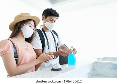 Asian Couple Traveler Wear Mask And Clean Hand Or Hand Washing Before Check-in At Desk Front Hotel Reception In Coronavirus Or Covid19 Spread