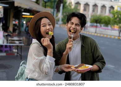 Asian couple traveler wearing a casual wear and hat in relationship buying a dessert snack on street food market in the evening. Backpacker traveling in Bangkok, Thailand.. - Powered by Shutterstock