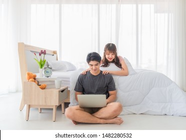 Asian couple is using laptop surfing on the Internet in bedroom with happiness in holiday.  Lifestyle and relaxation concept. - Powered by Shutterstock