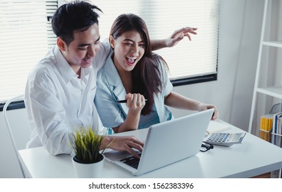 Asian Couple Using And Looking Laptop With Happy Together In The Home. Success Of Lovers In Front Of A Notebook. Happy Couple On Social Online With A Laptop.