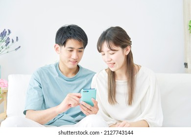 Asian Couple Using The Smartphone At Home