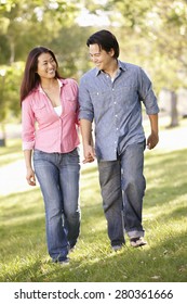 Asian Couple Walking Hand In Hand In Park