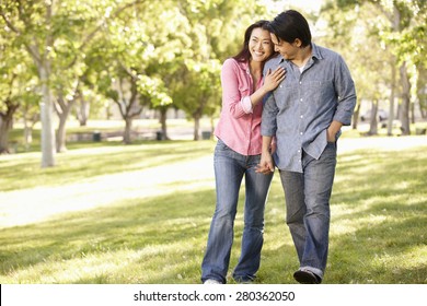 Asian Couple Walking Hand In Hand In Park