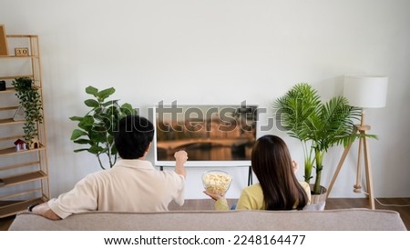 Asian couple watching tv together relaxing at home Enjoying Watching Television.