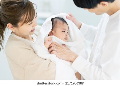 Asian Couple Wiping Baby With Bath Towel. Child Rearing. Parenting. Newborn.