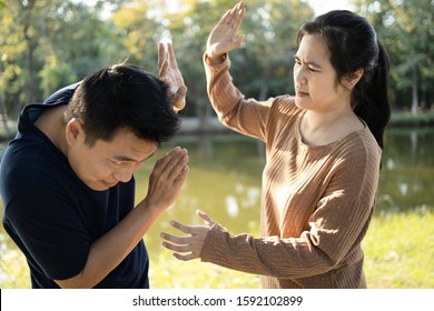 Asian couple,husband afraid to his wife,woman swings to hit fighting a man,female people slapping,threatening scared man, male trying protect himself by raising hand guarding her,conflict,argument