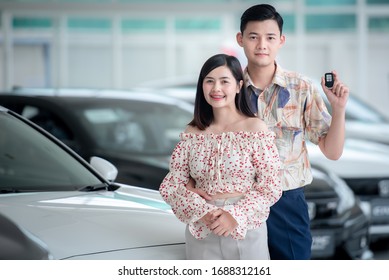 Asian Couples Are Happy To Buy A New Car In The Showroom. Concept Of Car Buying And Concept Of Success