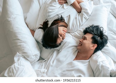 Asian Couples Is Laying On Bed In The Bed Room At Modern Home.Couple In Valentine Day.Love Couple,Relationship And Couple Concept.