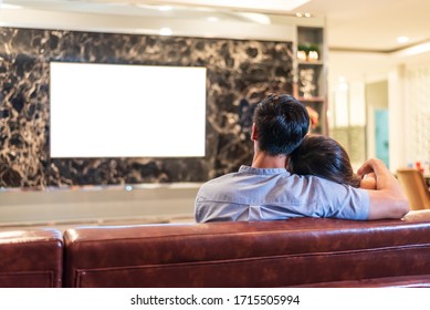 Asian couples watching white blank screen display television for advertising template background.  People lifestyles concept. Lockdown social distancing work from home. Selective focus on couples