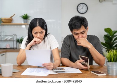 Asian couples are worried about debt and expenses. Stressful women and men receive bank loan invoices. credit card , water, electricity , telephone bills. No money and broke - Shutterstock ID 2089492840
