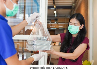 Asian Courier Or Food Delivery Man Service In Protective Mask And Medical Gloves Delivers Takeaway Food To Customer At Home Under Quarantine Coronavirus Outbreak Covid-19 Pandemic