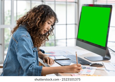 Asian creative female graphic designer working with color palettes on a tablet in modern workspace, with green screen - Powered by Shutterstock