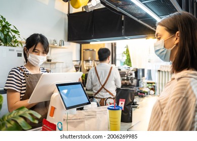 Asian Customer Girl Ordering Takeaway Food With Waiter Worker At Cafe. Business Owner Barista Woman In Apron Wear Mask Due To Covid19 Pandemic, Work In Restaurant Serve Occupation Service Young Girl.