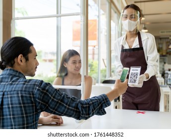 Asiatische Kunden scannen QR-Code online Menü von Kellnerin mit Gesichtsmaske und Gesichtsschild. Der Kunde saß auf einem sozialen Distanztisch für neue normale Lebensweise im Restaurant nach Coronavirus covid-19 pamdemic.