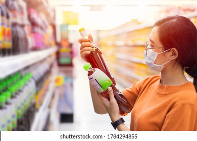 Asian Customer Shopping In Supermarket With Face Mask Choice Select And Compare Fish Sauce By Reading Products Detail Label On Shelf