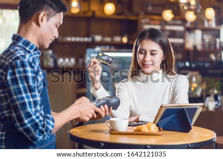 Asian customer woman paying with credit card via contactless nfs technology to Asian Small Coffee shop owner at the female table in cafe, Small business owner and startup in coffee shop concept
