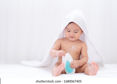 Asian cute baby wearing white towel after taking a shower applying moisturizing cream baby lotion,Childhood baby health  care and skin care concept.