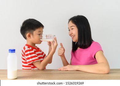 Asian Cute Boy Drinking Milk With His Mother, White Wall At Home, .Food And Drink Concept With Copy Space