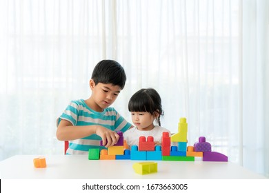 Asian Cute Brother And Sister Play With A Toy Block Designer On The Table In Living Room At Home. Concept Of Bonding Of Sibling, Friendship And Learn Through Play Activity For Kid Development.