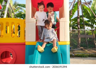 Asian Cute Brother And Sisters Having Fun Playing On A Slide In Playground At Home Backyard On Summer Sunny Day On Nature, Healthy Kid Sliding Down Slide, Fun Outdoor Exercises, Selective Focus