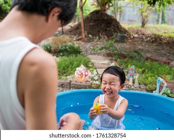 Asian Cute Child Boy Laughing While Playing Water In Blue Bowl With Father In Rural Nature. Young Kid Having Happy Moment In Summer. Family Activity At Home And Preschool Concept.