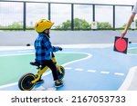 Asian cute child learns to ride a balance bike with a yellow helmet. Stop waiting for the red light , learning traffic rules ,motion blur image